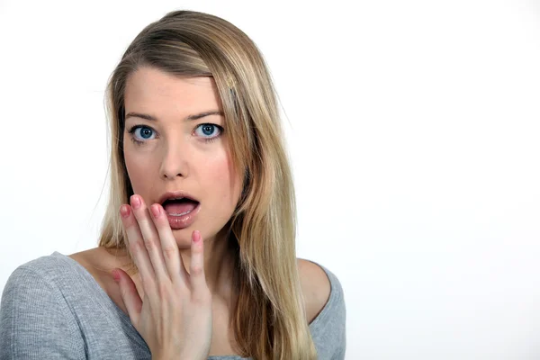Blonde looking surprised with fingers before mouth — Stock Photo, Image