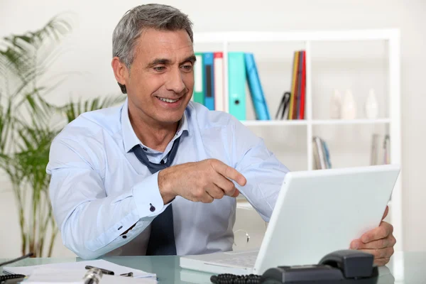 Senior obchodník směřující na laptop — Stock fotografie