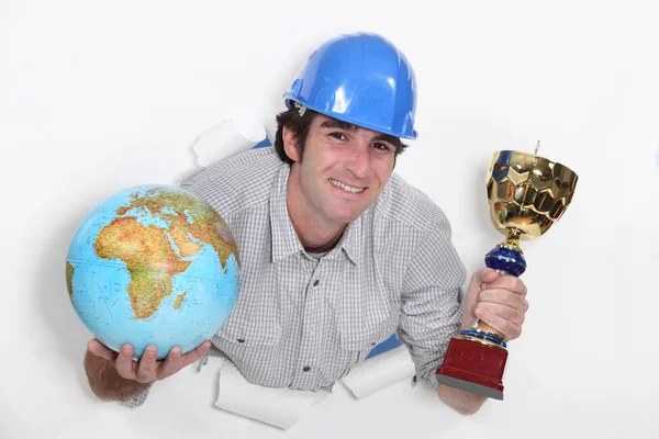 Craftsman all smiles holding trophy and globe — Stock Photo, Image