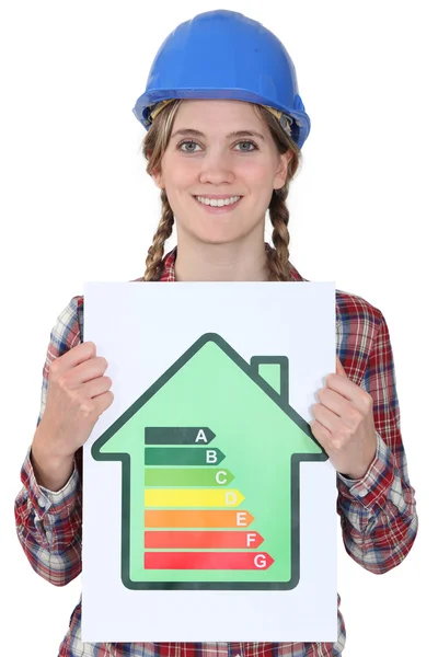 Smiling tradeswoman holding up an energy efficiency rating chart — Stock Photo, Image