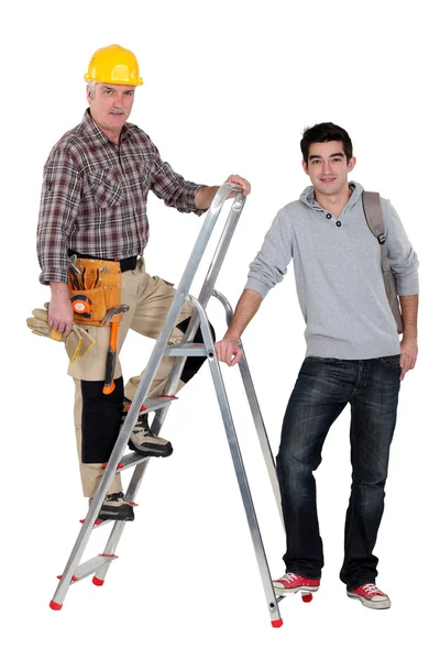 Constructor de pie en la escalera junto a aprendiz —  Fotos de Stock