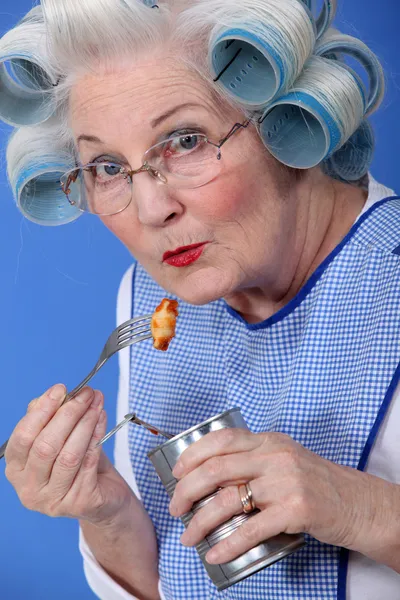 Oudere vrouw eten uit blikje — Stockfoto