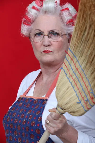 Stern elderly lady holding broom — Stock Photo, Image
