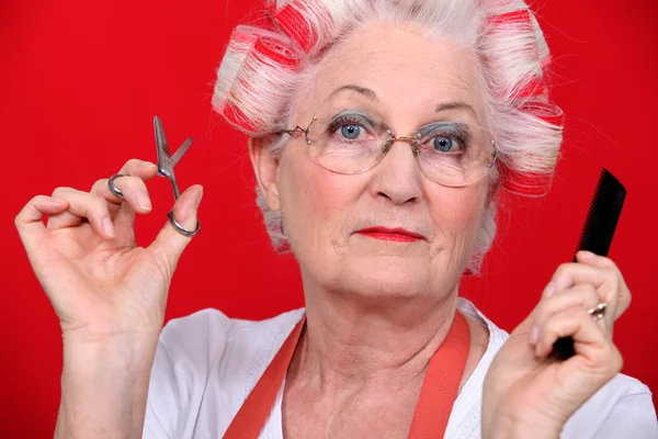 Grootmoeder met een schaar en haircurlers — Stockfoto