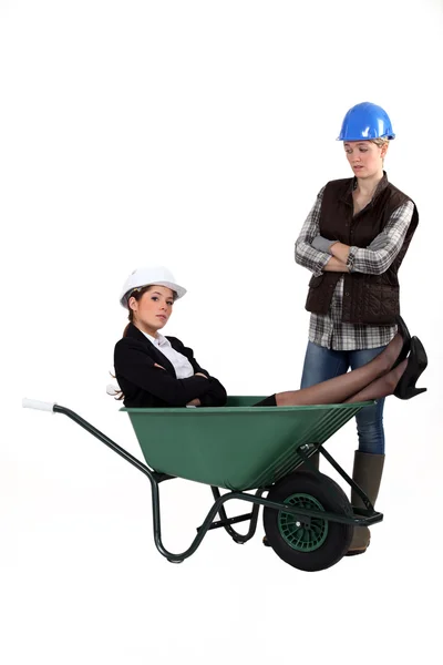 Architect laying in wheelbarrow whilst worker watches — Stock Photo, Image