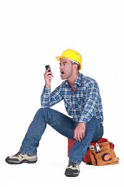 Craftsman irritado olhando para seu telefone celular — Fotografia de Stock