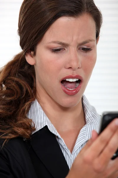 Frau starrt ungläubig auf ihr Handy — Stockfoto