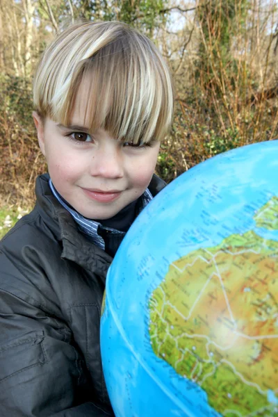 Маленький мальчик держит земной шар на открытом воздухе — стоковое фото