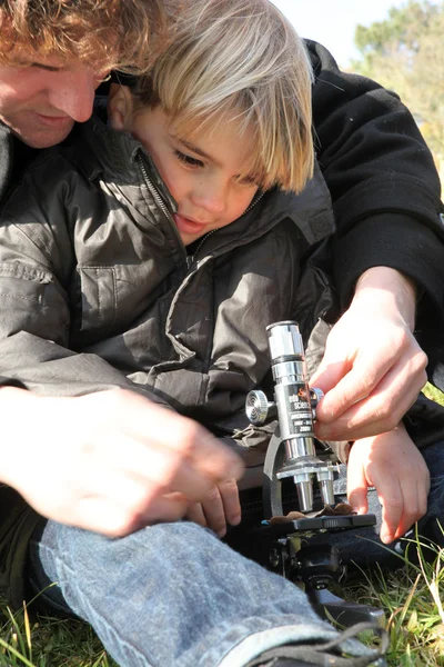 Père et utilisation du microscope dans un champ — Photo