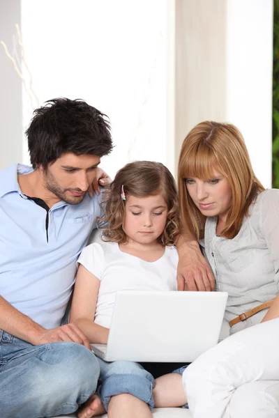 Casal com filha e laptop no sofá — Fotografia de Stock