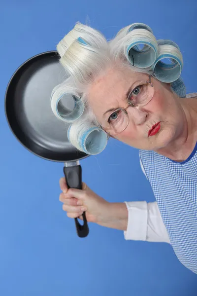 Boos oude dame dreigt te gebruiken koekenpan Stockafbeelding