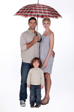 Young family standing underneath an open umbrella clipart