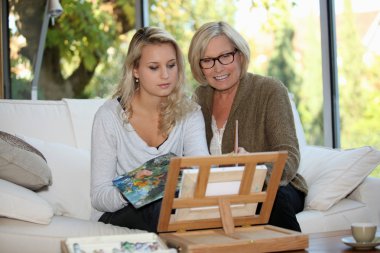 Grandmother and granddaughter painting on the veranda clipart