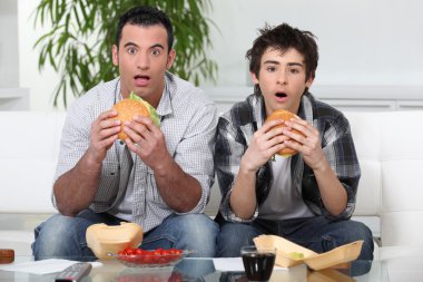 Brothers staring in amazement while eating a hamburger clipart