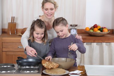 Mum and girls making pancakes clipart