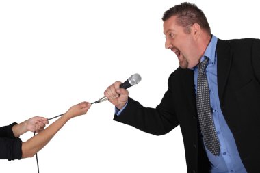 Businessman struggling to keep hold of a microphone clipart