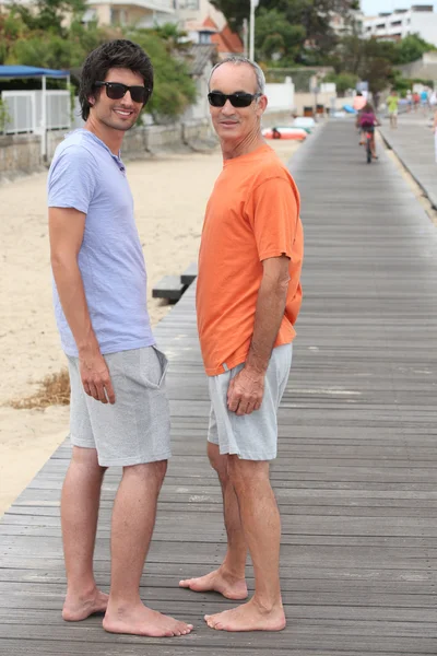 Großvater und Enkel laufen am Strand entlang — Stockfoto