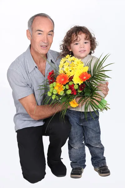 En morfar och hans lille son håller en bukett blommor — Stockfoto