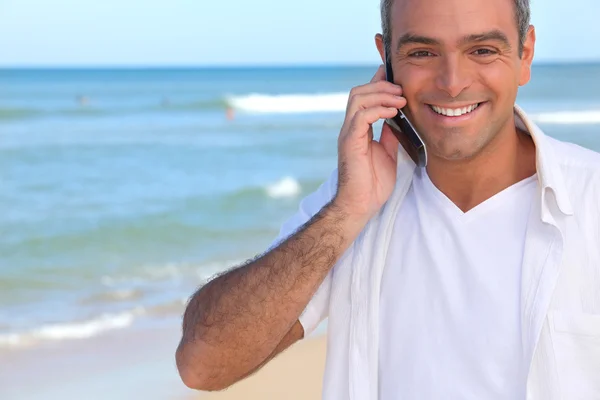 Man taking a call whilst at the beach — Stock Photo, Image