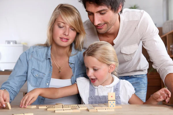 Feliz casal jogar dominós com filha — Fotografia de Stock