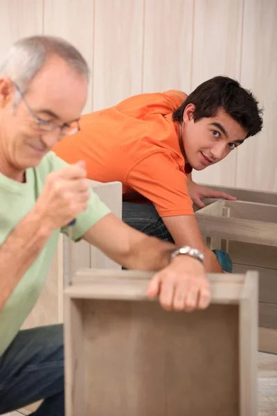 Дедушка с внуком собирает мебель — стоковое фото