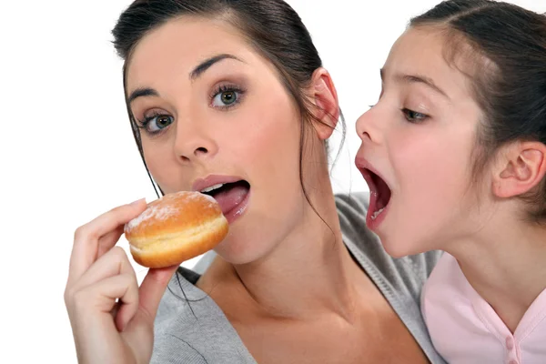 Woman and child fighting over a doughnut — Stock Photo, Image