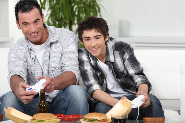 Πατέρας και γιος, βιντεοπαιχνίδια, ενώ τρώει fast-food — Φωτογραφία Αρχείου