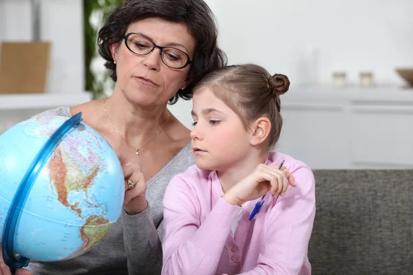 Grootmoeder met kleindochter kijken naar globe — Stockfoto