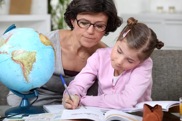 Žena pomoci dítě s její geografie úkoly — Stock fotografie