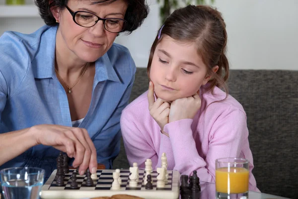 Flickan och hennes mormor spelar schack — Stockfoto