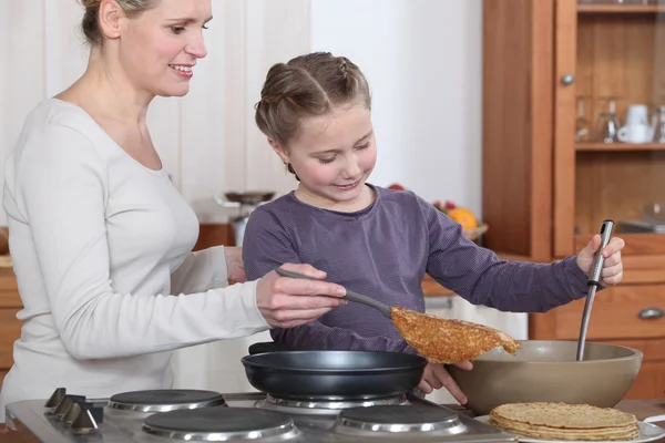 Mujer enseñando a su hija a hacer crepes —  Fotos de Stock