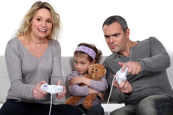 Homem e mulher jogando para jogos de vídeo com a menina bebendo — Fotografia de Stock