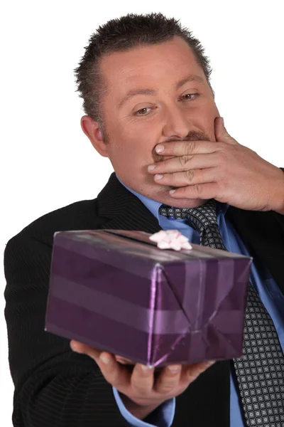 Portrait of a man surprised in front of a gift package — Stock Photo, Image
