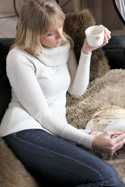 Mulher relaxante no sofá com caneca de café — Fotografia de Stock