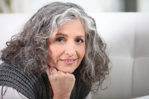Grey-haired woman resting chin on hand — Stock Photo, Image