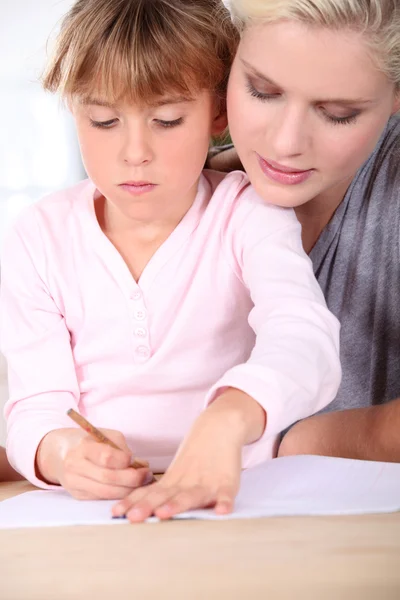 Mother teaching daughter to write Stock Photo