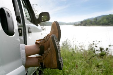 Man snoozing in car parked by lake clipart