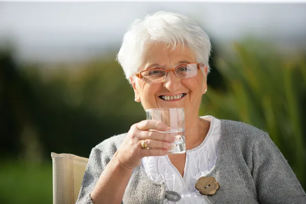 Idős nő egy pohár vízzel — Stock Fotó