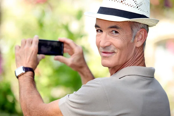 Мужчина средних лет фотографирует во время ношения соломенной шляпы — стоковое фото