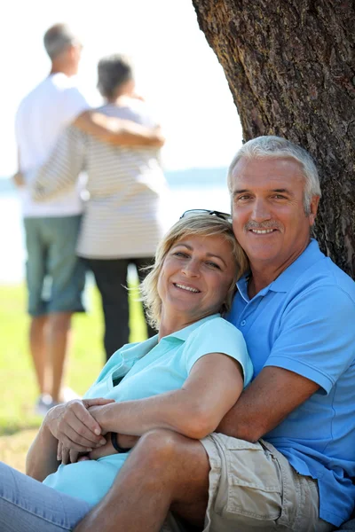 Älteres Paar lehnt sich an Baumstamm — Stockfoto