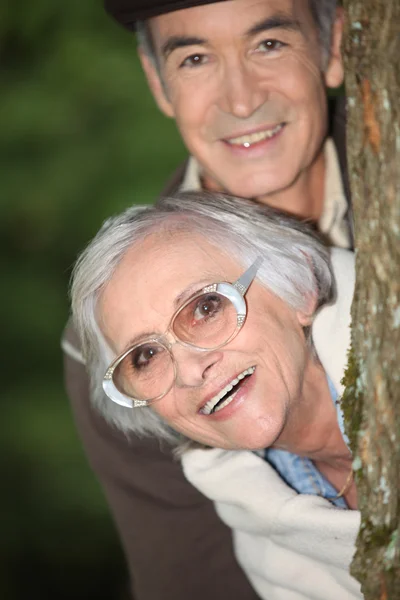 Casal sênior atrás de uma árvore — Fotografia de Stock