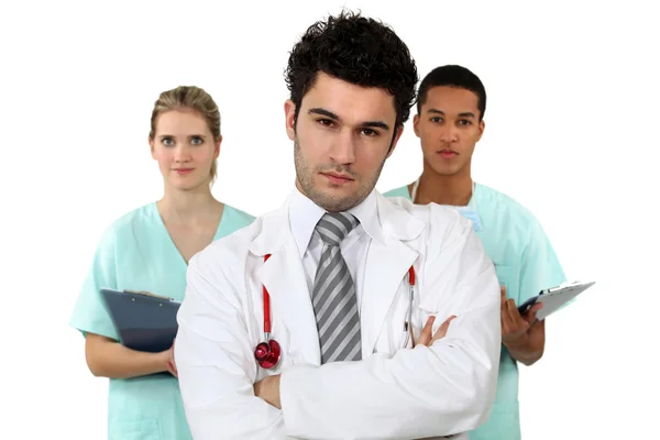 Fiatal orvos kereszt-fegyveres férfi és női ápolók háttérben álló — Stock Fotó