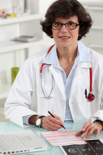 Médico feminino que escreve prescrição — Fotografia de Stock