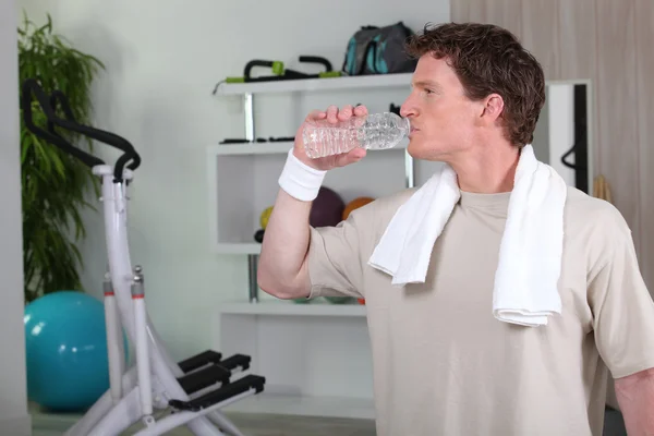 Hombre beber agua después de dura sesión de gimnasio — Foto de Stock