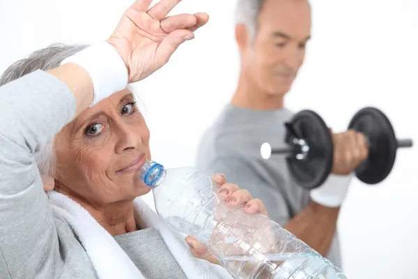 Elderly woman drinking water after gym session — Stock Photo, Image