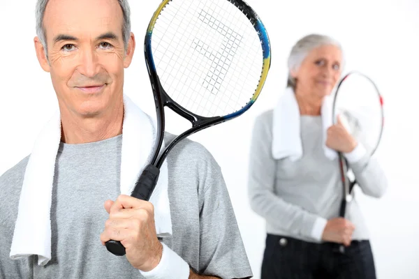 Couple aîné avec raquettes de tennis — Photo