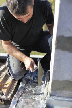 Mason using trowel to spread cement on wall clipart