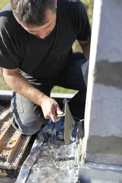 Mason rozprzestrzeniania cementu na ścianie za pomocą kielni — Zdjęcie stockowe