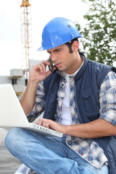 Trabajador de la construcción con ordenador y teléfono —  Fotos de Stock