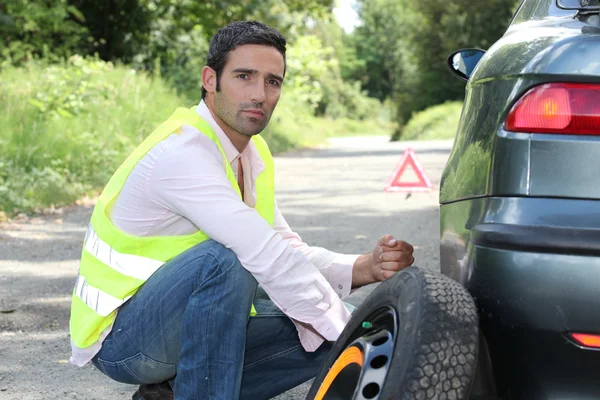 男は、道路の側にタイヤを変更します。 — ストック写真